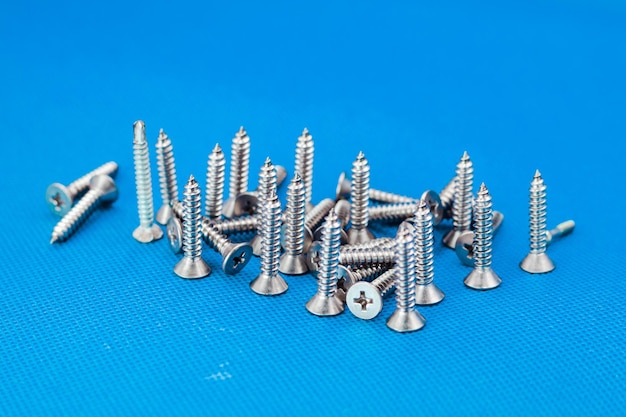 Tapping screws made of steel on blue or water color background metal screw iron screw chrome screw screws as a background wood screw concept industry copy space for text