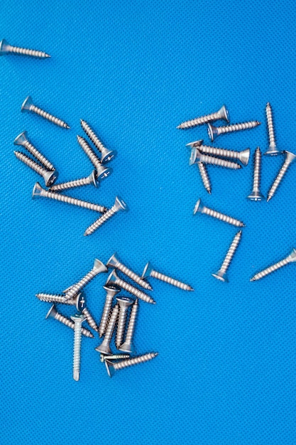 Tapping screws made of steel on blue or water color background metal screw iron screw chrome screw screws as a background wood screw concept industry copy space for text