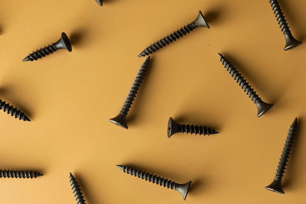 Tapping screws made of steel on orange background metal screw iron screw chrome screw screws as a background wood screw concept industry copy space for text