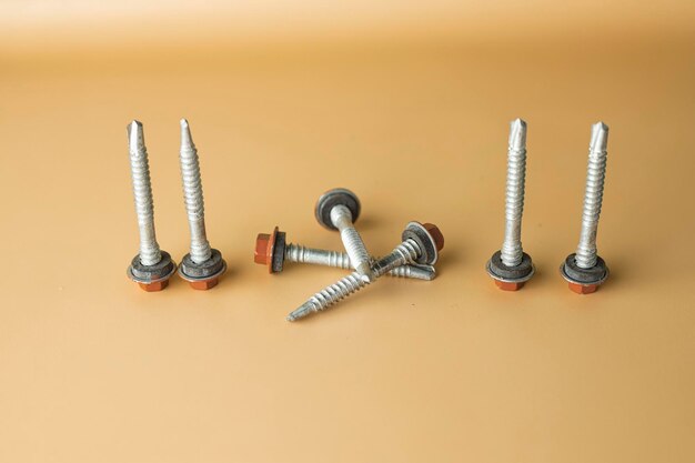 Photo tapping screws made of steel on orange background metal screw iron screw chrome screw screws as a background wood screw concept industry copy space for text