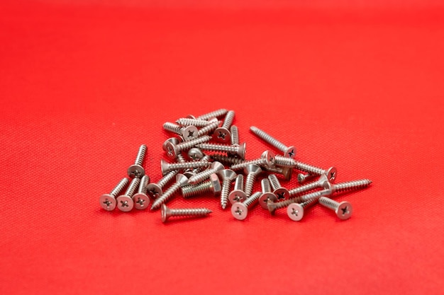 Tapping screws made of steel on red color background metal screw iron screw chrome screw screws as a background wood screw concept industry copy space for text