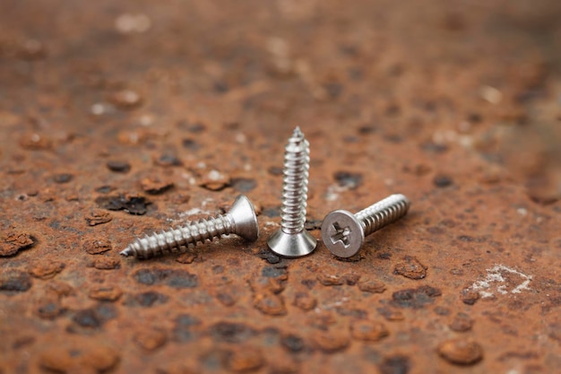 Tapping screws made of steel on steel rusty background metal screw iron screw chrome screw screws as a background wood screw concept industry copy space for text