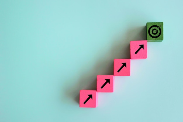 Target and focus concept Wooden cubes line upward with arrow and dart target on green background