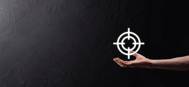 Targeting concept with businessman hand holding target icon dartboard sketch on chalkboard. Objective target and investment goal concept.