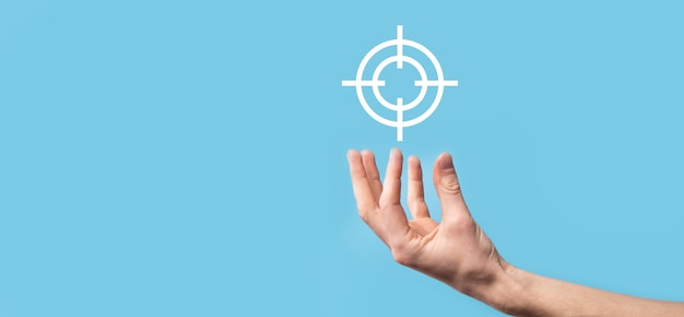 Targeting concept with hand holding target icon dartboard\
sketch on chalkboard. objective target and investment goal\
concept.