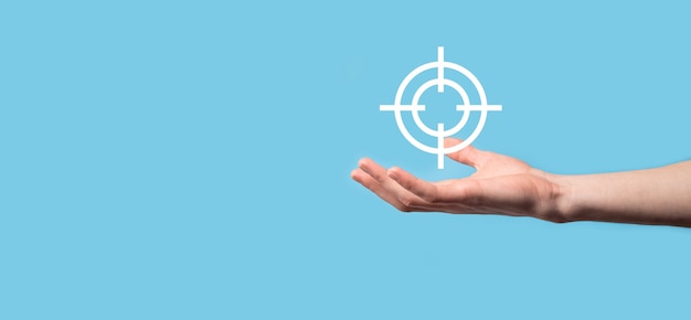 Targeting concept with hand holding target icon dartboard sketch on chalkboard.