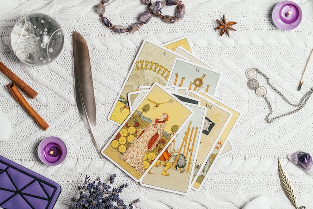 Foto tarotkaarten liggen open op een wit gebreid oppervlak met kristallen bol, lavendel, kaarsen. minsk, wit-rusland, 11.10.2021