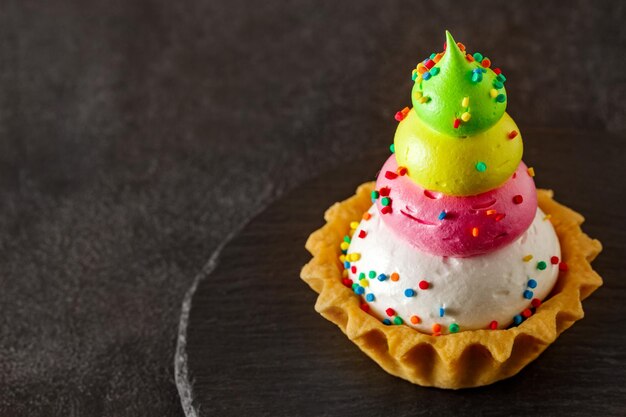 Tart cake with four layers of cream on slate stone plate round dark background selective focus