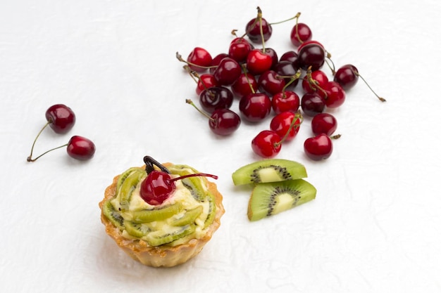Tart decorated with red cherry and kiwi Kiwi and red cherry on white background Top view Copy space