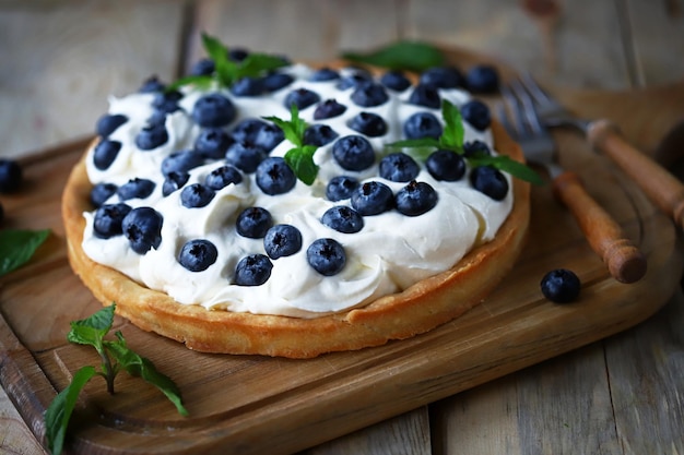 Tart with blueberries and white buttercream. Summer berry dessert.