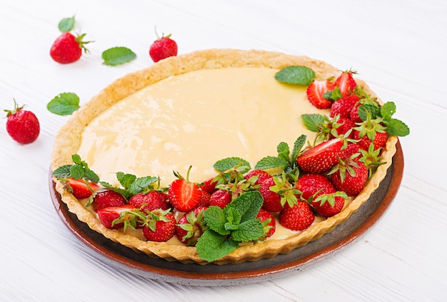 Tart with strawberries and whipped cream decorated with mint leaves