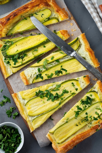 Tart with zucchini, ricotta cheese and parsley on a dark concrete background