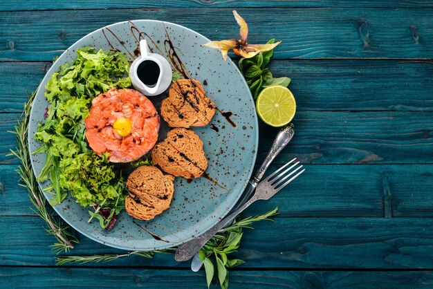 Tartar with salmon and avocado On a wooden background Top view Copy space