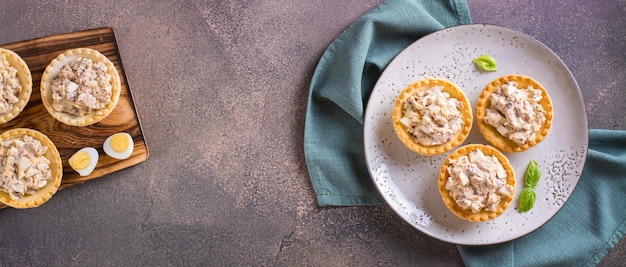 Tartlets filled with canned fish eggs and mayonnaise on a plate top view web banner