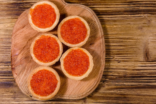 Tartlets met rode kaviaar op een houten snijplank. Feestelijk eten. Bovenaanzicht