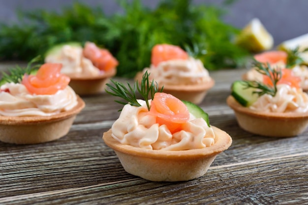 Tartlets met roomkaas en gezouten zalm op een houten ondergrond. lekkere lichte snack voor een feestje. fingerfood.