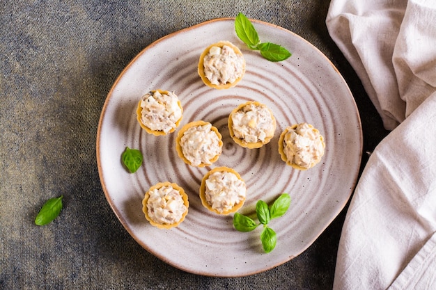 Tartlets with canned fish salad eggs and mayonnaise on a plate Homemade snacks Top view Closeup