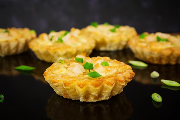 Tartlets with chicken and zucchini on dark 