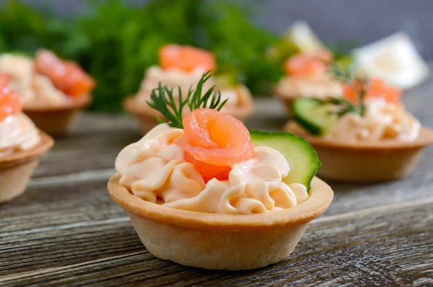 Tartellette con crema di formaggio e salmone salato su fondo di legno. spuntino leggero e gustoso per una festa. cibo da mangiare con le mani.