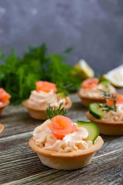 Tartlets with cream cheese and salted salmon on a wooden background. Tasty light snack for a party. Finger Food.