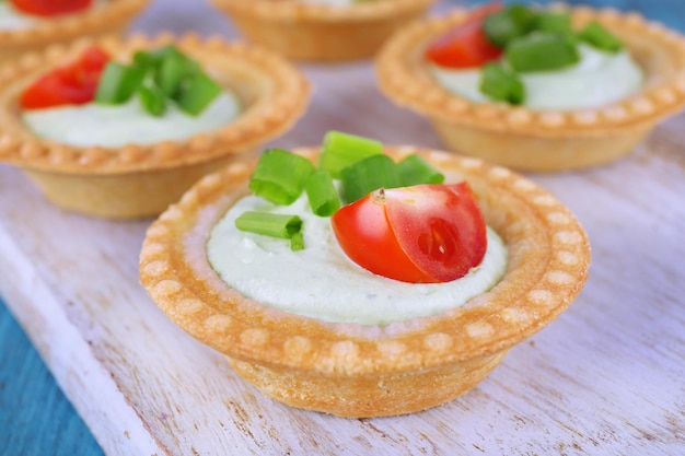 Tartlets with greens and vegetables with sauce on table closeup