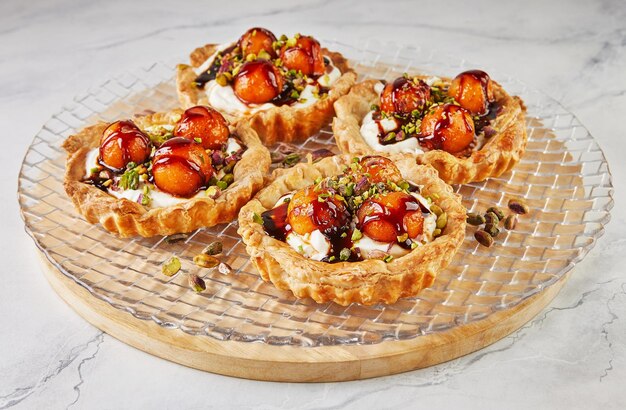 Tartlets with melon mascarpone and pistachios on transparent plate