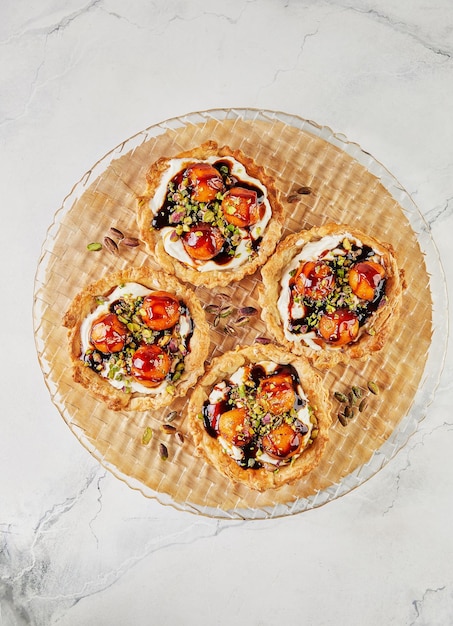 Tartlets with melon mascarpone and pistachios on transparent plate