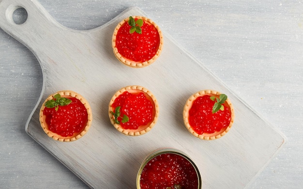 Tartlets with red caviar on a light background closeup top view no people