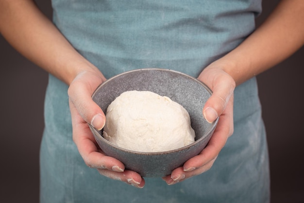 Tarwe deeg bakker houdt kom met meel brood of pizza bereiden ingrediënten voor voedsel bakken gebak