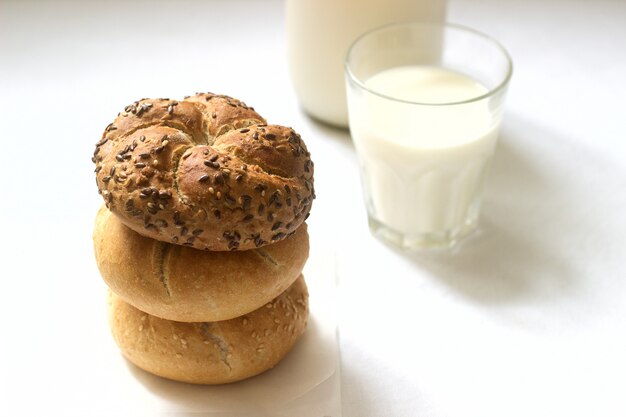 Tarwe- en rogge Kaiserbroodjes met vlas en sesamzaadjes geserveerd met melk, gezond ontbijt.