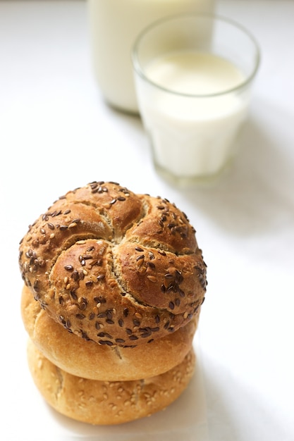 Tarwe- en rogge Kaiserbroodjes met vlas en sesamzaadjes geserveerd met melk, gezond ontbijt.