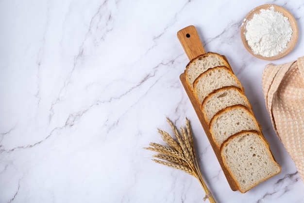 Tarwe oren meel en gesneden brood op een lichte marmeren tafel Bovenaanzicht