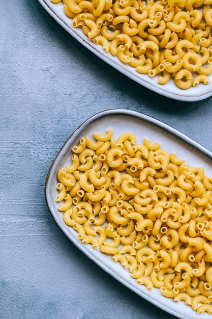 Tarwe rauwe Italiaanse pasta in platen geïsoleerd op blauwe achtergrond.