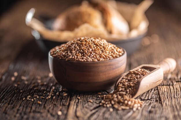 Tarwekorrels-het belangrijkste ingrediënt van het brood gevuld in houten kom en houten rustieke schep. Bakend knapperig brood op de achtergrond.