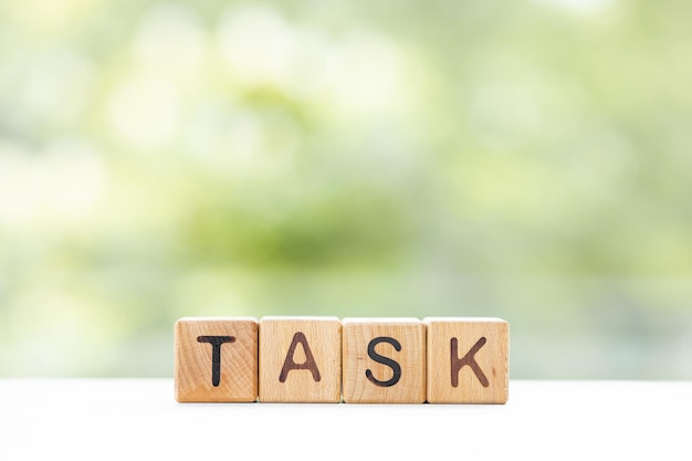 Task word is written on wooden cubes on a green summer background Closeup of wooden elements