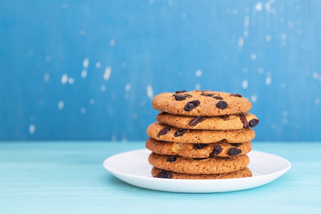 Tasly cookies with raisins on a white plate. Blue backdrop