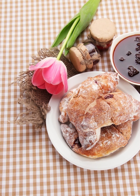 Taste croissants on plate and jam on tablecloth