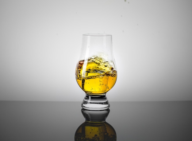 Taster Glass with a Dram of Scotch Whisky and Ice Cube Falling into it