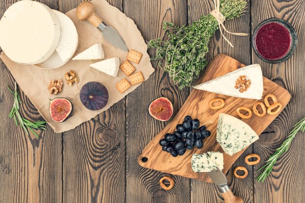 Tasting cheese dish with herbs and fruits on wooden table