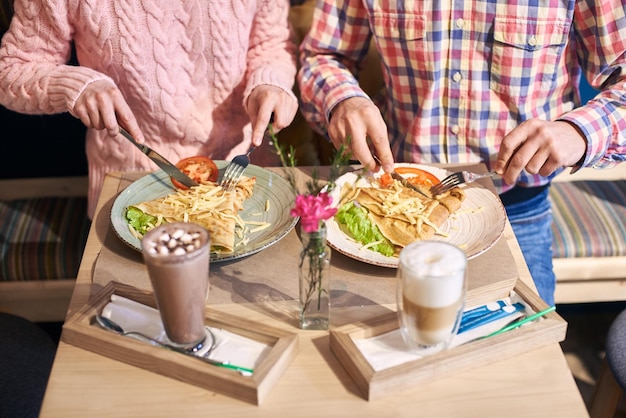 フォアグラウンドで飲み物と花を添えたダイニングテーブルで美味しい料理を味わうトリミングされた一般的なビュー