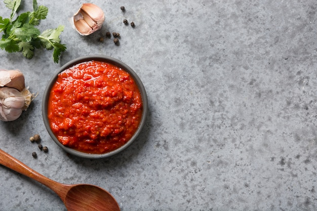 Tasty ajvar. Vegetable sauce or caviar of baked red bell pepper on grey. Balkan cuisine. 