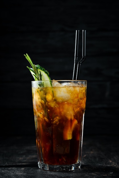 Gustoso cocktail alcolico cola whisky cetriolo e ghiaccio su sfondo di legno vista dall'alto