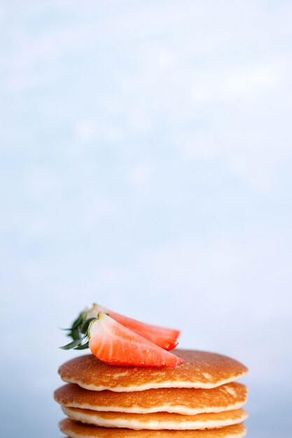 파란색 배경에 흰색 접시에 딸기와 맛있는 미국 팬케이크