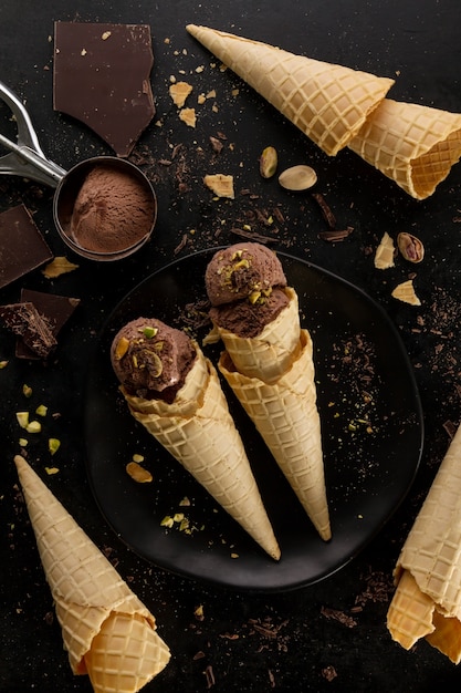 Gelato gustoso al cioccolato appetitoso con menta e pistacchi in piccoli coni su sfondo scuro. processo di cottura. vista dall'alto.