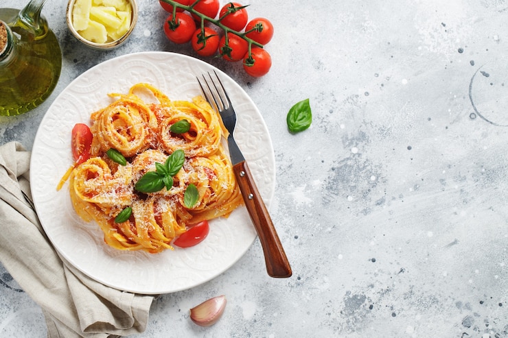 Photo tasty appetizing classic italian tagliatelle pasta with tomato sauce, cheese parmesan and basil on plate on light table. view from above, horizontal. top view with copy space.