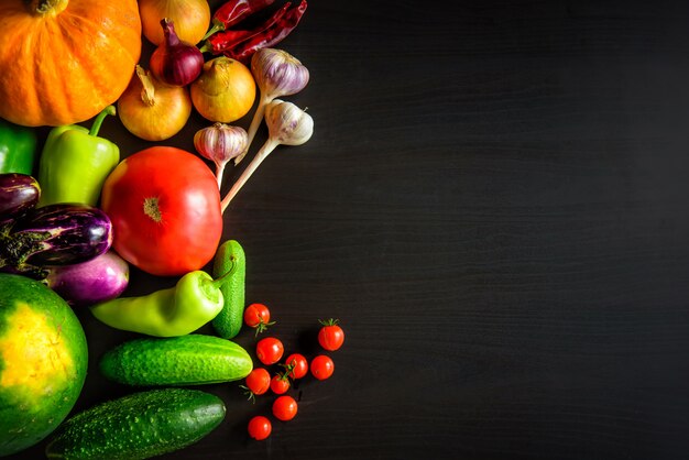 Tasty appetizing fresh autumn seasonal vegetables on dark wooden table top view with copyspace. Healthy food, vegetarianism, clean eating. Harvest, gardening