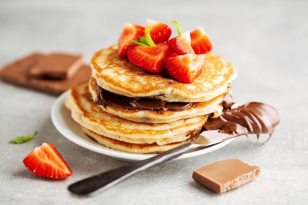 Tasty appetizing freshmade pancakes decorated with strawberry and chocolate paste served for breakfast. Closeup