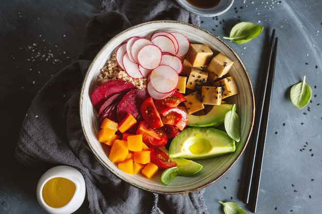 Tasty appetizing vegan bowl with vegetables and tofu served in bowl. Closeup.