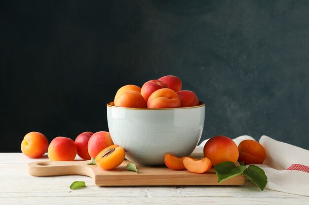 tasty apricots on wooden table against dark background