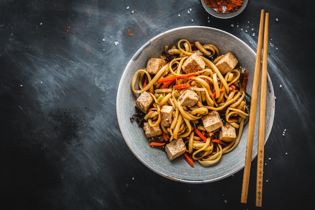 Tasty asian noodles with cheese tofu and vegetables in bowls.